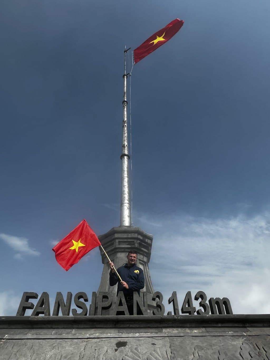 Vietnamese vlag onder de vlaggenmast op de top van de Fansipan met blauwe lucht