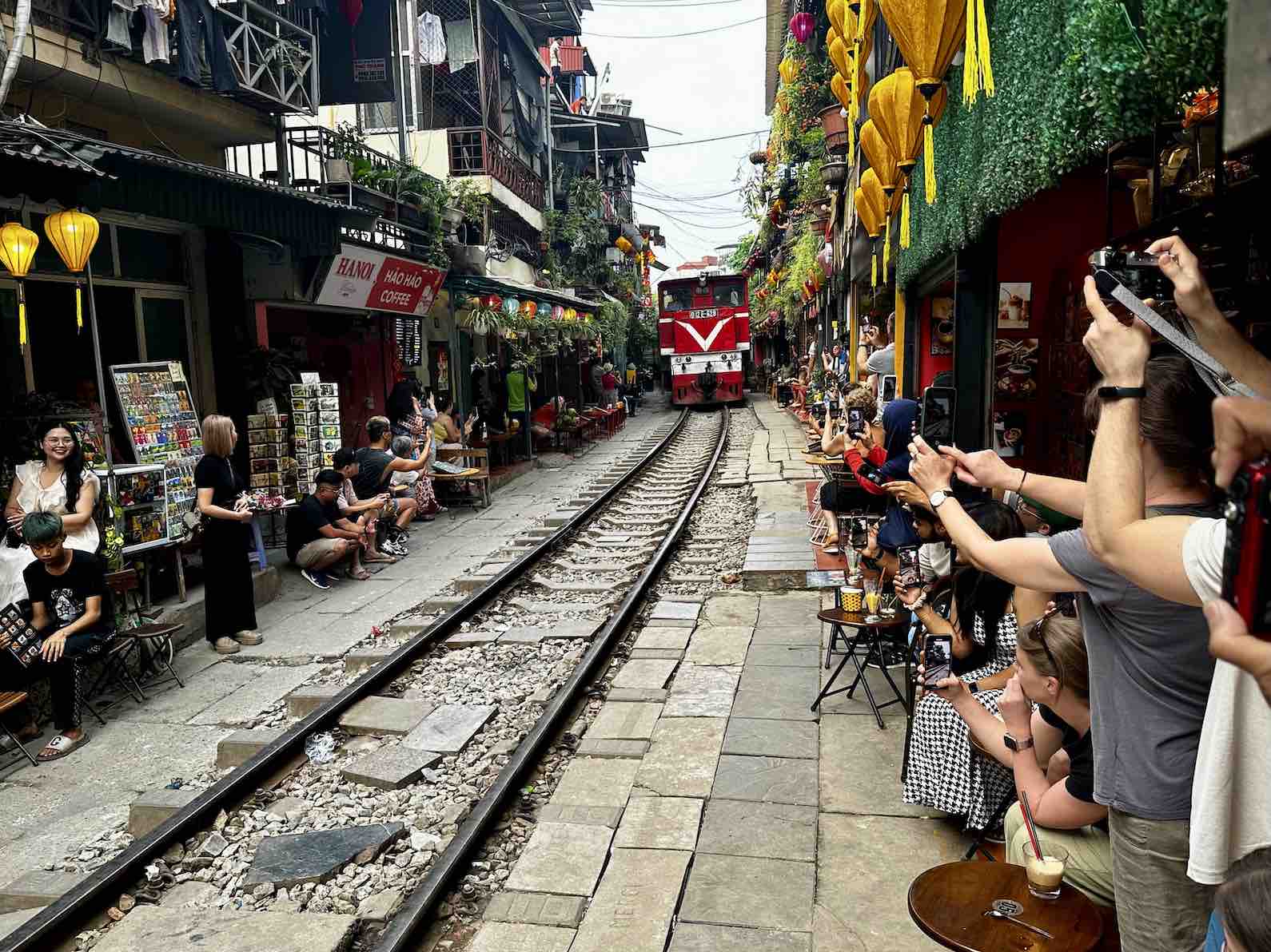 Een trein rijdt door de Train Street in Hanoi tussen cafés en huizen