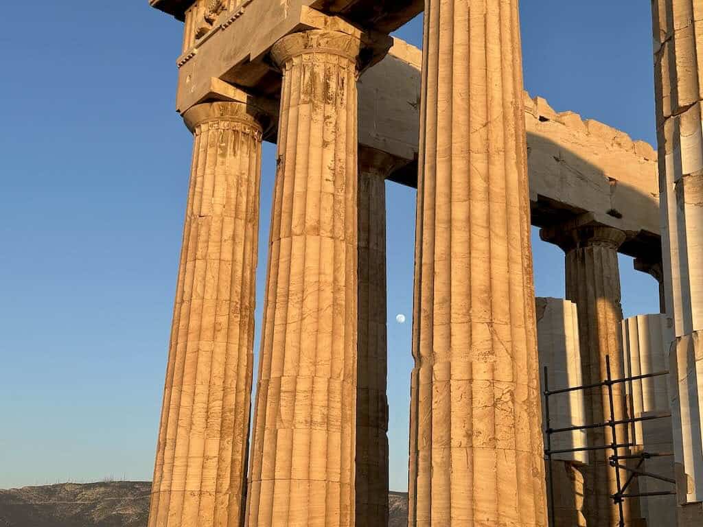 Parthenon at sunset with the moon rising between its columns in Athens
