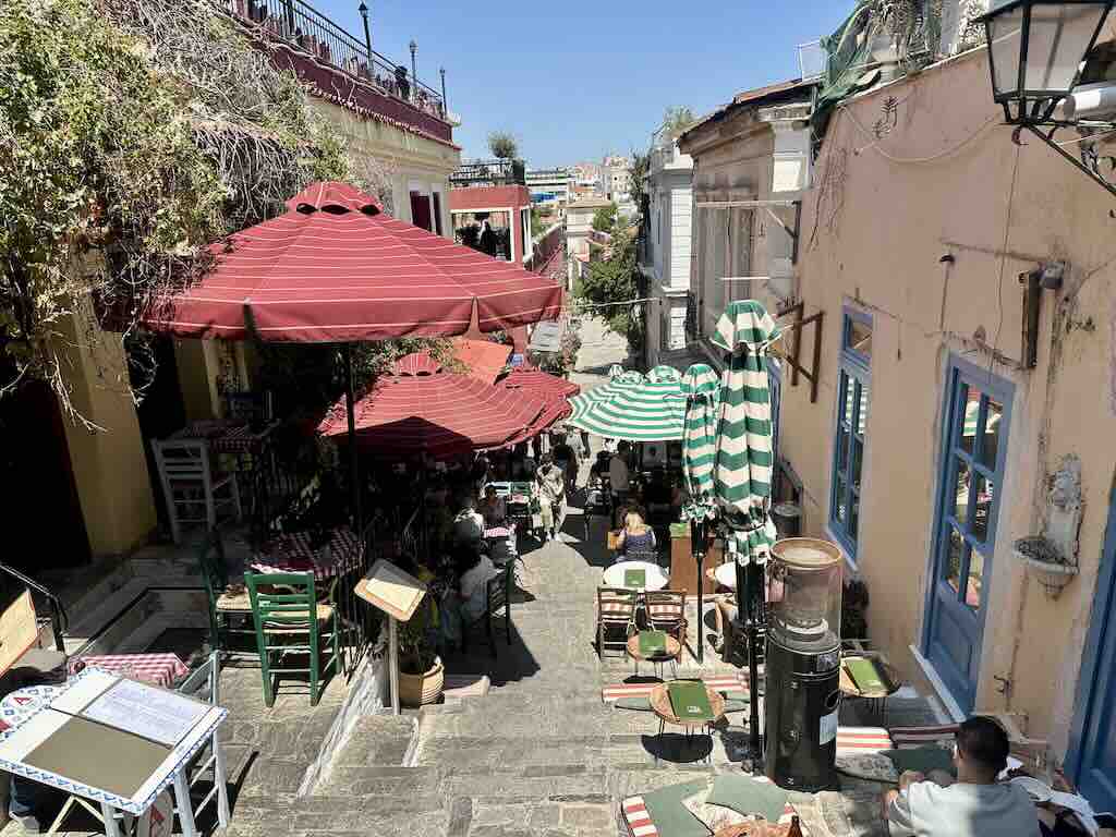 Lively street in Plaka Athens with red umbrellas and outdoor restaurants