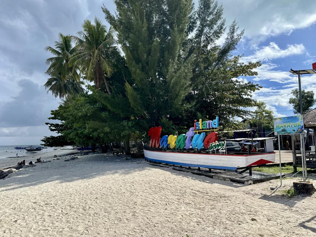 White-sand beach and palms on arrival at Maratua Island, Indonesia