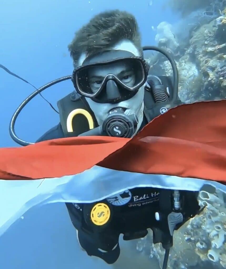 Mergulhador segurando a bandeira da Indonésia debaixo d'água na ilha de Menjangan, Bali, no Dia da Independência