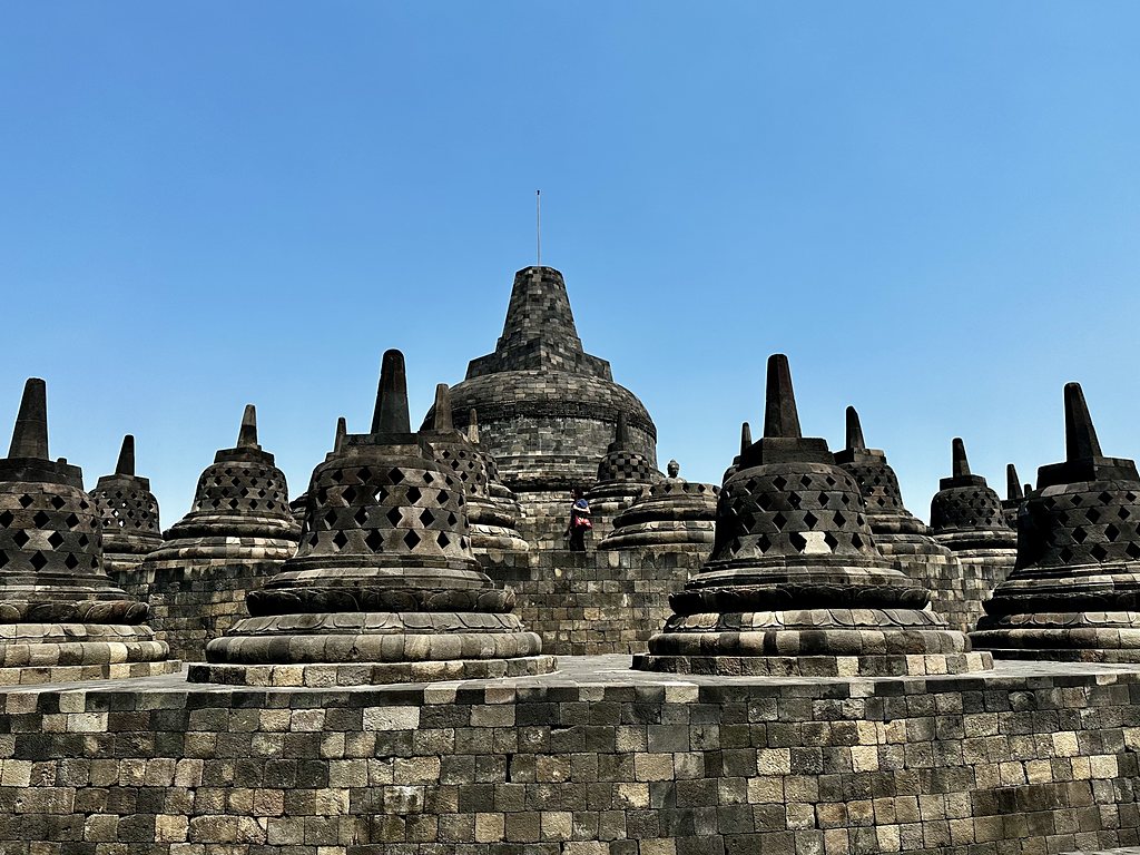 The bell-shaped perforated stupas on the upper circular terraces of Borobudur against a blue sky, Java, Indonesia