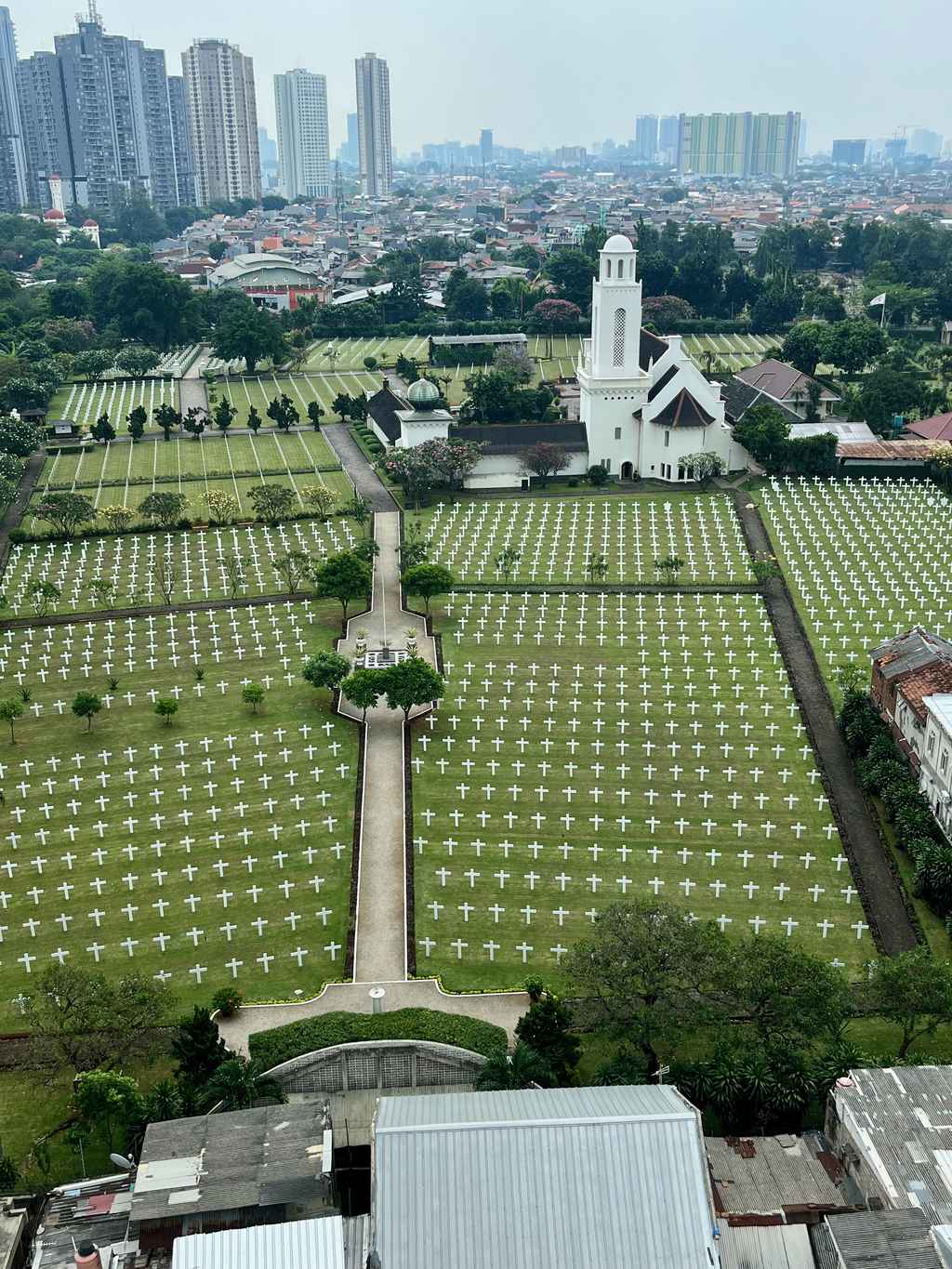 The Ereveld Menteng Pulo Dutch war cemetery in South Jakarta with the Kuningan towers behind