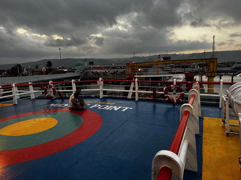 Deck of the Ketapang to Gilimanuk ferry leaving Java at dusk under a storm sky