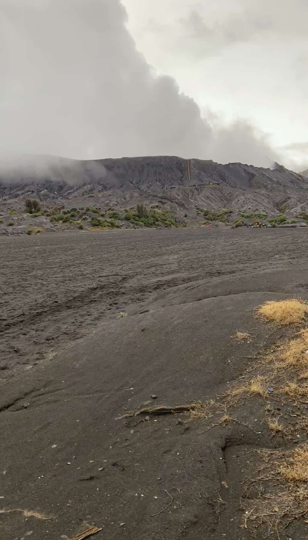 De hellingen van Mount Bromo die na de regen uit de wolken opdoemen, januari 2021, Oost-Java