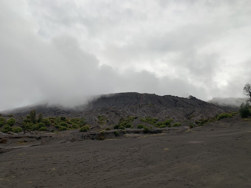 De zandzee bij Mount Bromo onder zware lage bewolking in het regenseizoen, met de calderawand nauwelijks zichtbaar