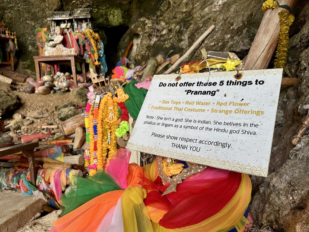 Der Phra-Nang-Schrein auf Railay mit bemalten Holzgaben und dem Hinweisschild, das um Respekt bittet