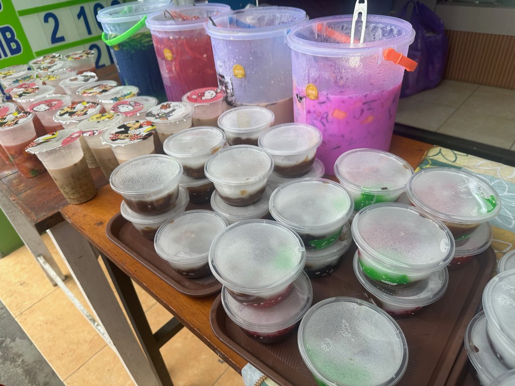 Ein Marktstand mit Eisgetränken in Bottichen und Gelee-Desserts in Bechern zum Mitnehmen, Indonesien