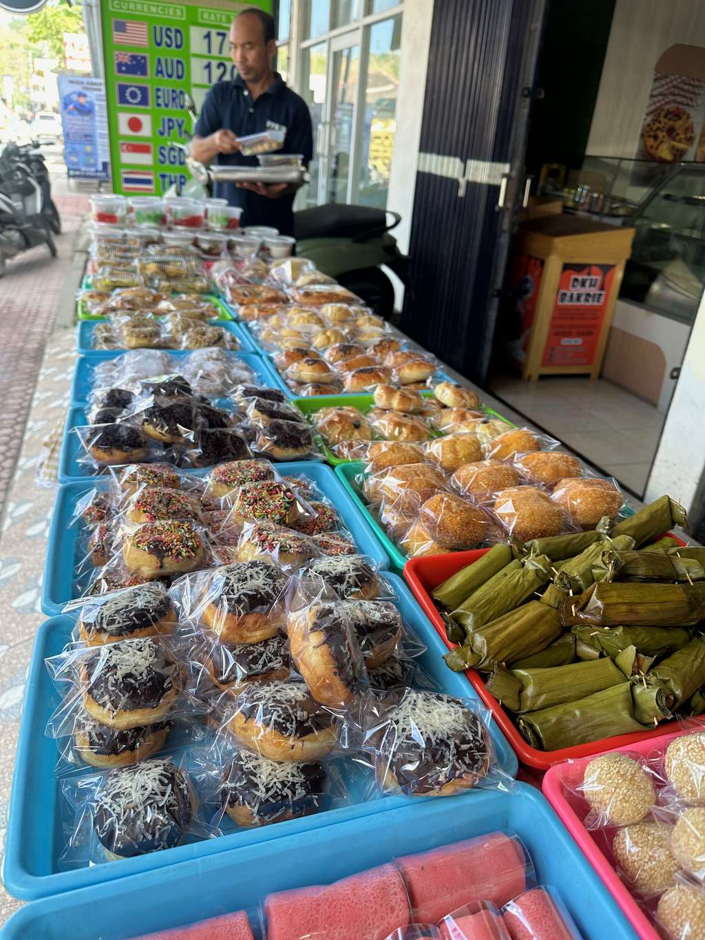 Ein jajanan-pasar-Stand mit Tabletts voller indonesischer Marktkuchen und Bananenblattpäckchen