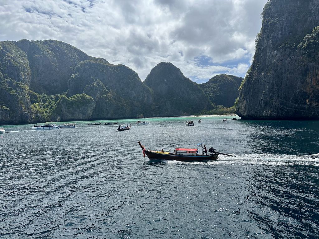 Winziges Longtailboot unter den Kalksteinwänden von Phi Phi Leh