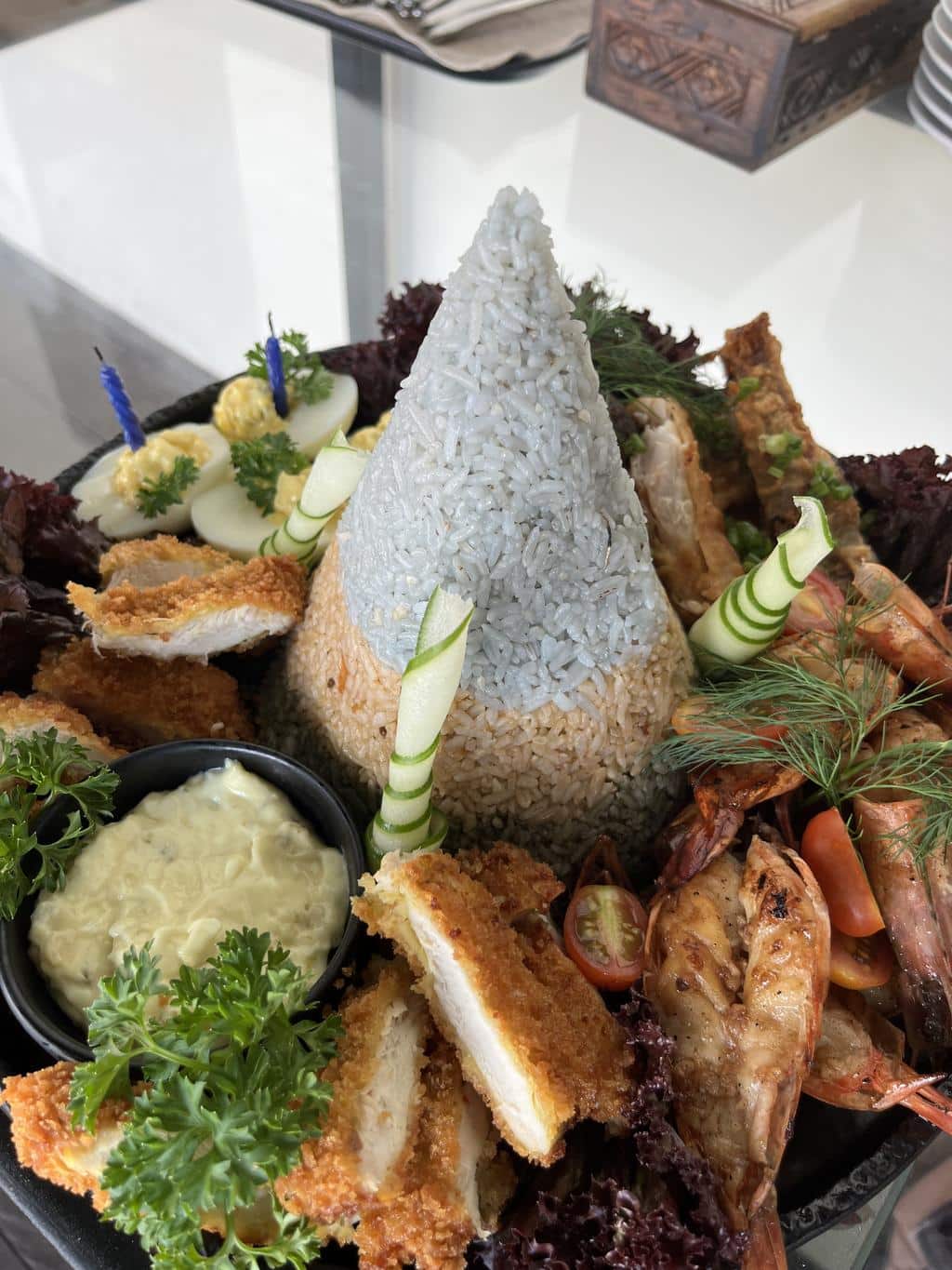 Nasi tumpeng, ein Reiskegel umgeben von gebratenem Hähnchen, Garnelen und Eiern, bei einer Feier auf Nusa Penida