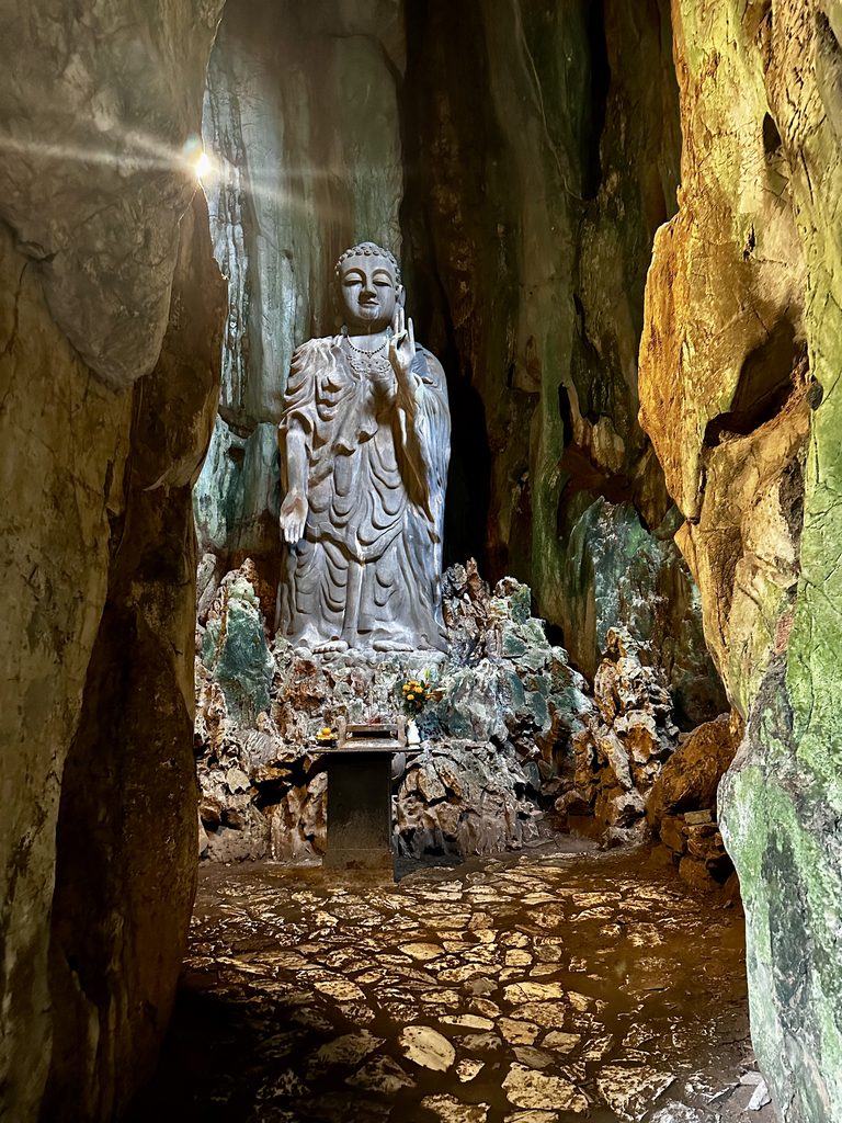 Patung Buddha berdiri yang dipahat dari marmer di dalam gua Pegunungan Marmer