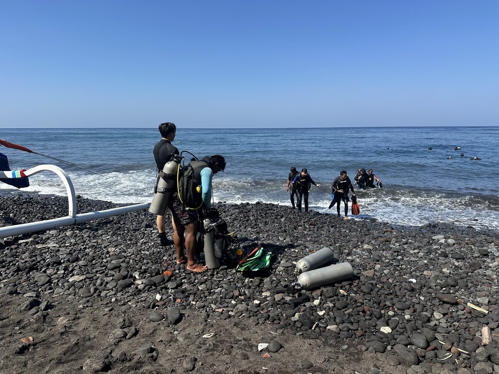 Sub che si vestono sui ciottoli neri di Tulamben prima di un’immersione da riva