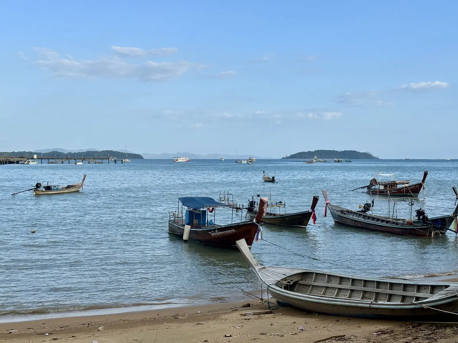 Barche long-tail sulla spiaggia accanto al molo di Ao Por, Phuket