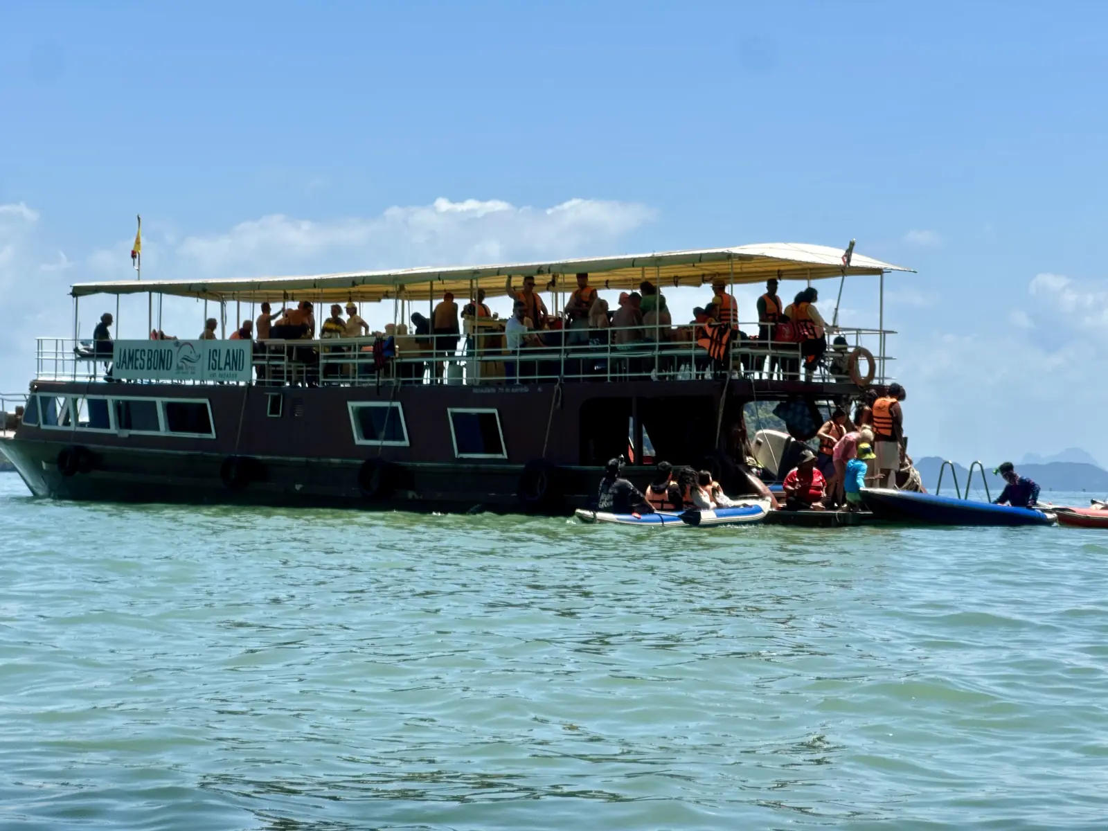 Grande barca di legno da escursione con i kayak all'ancora a Ko Panak, baia di Phang Nga