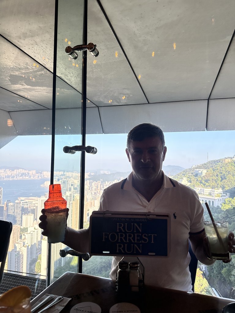 Blaise Jaeger在阿甘虾餐厅靠窗的桌边举着鸡尾酒,身后是香港天际线