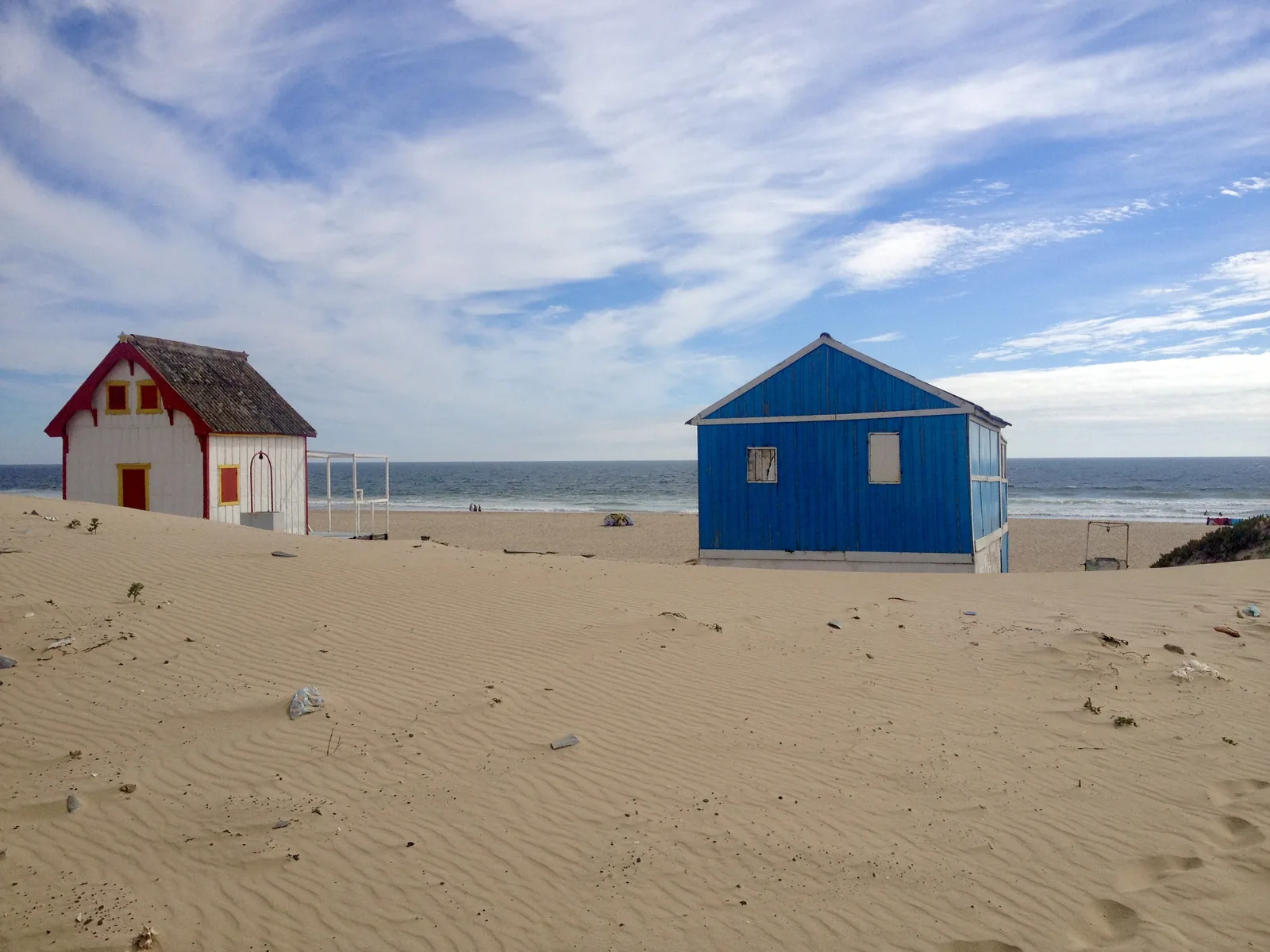 Blue and white beach huts on the sand of the Costa da Caparica