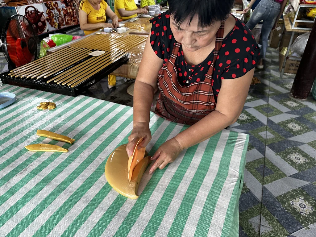 Een vrouw snijdt kokossnoep met de hand in een werkplaats in Ben Tre, Mekongdelta