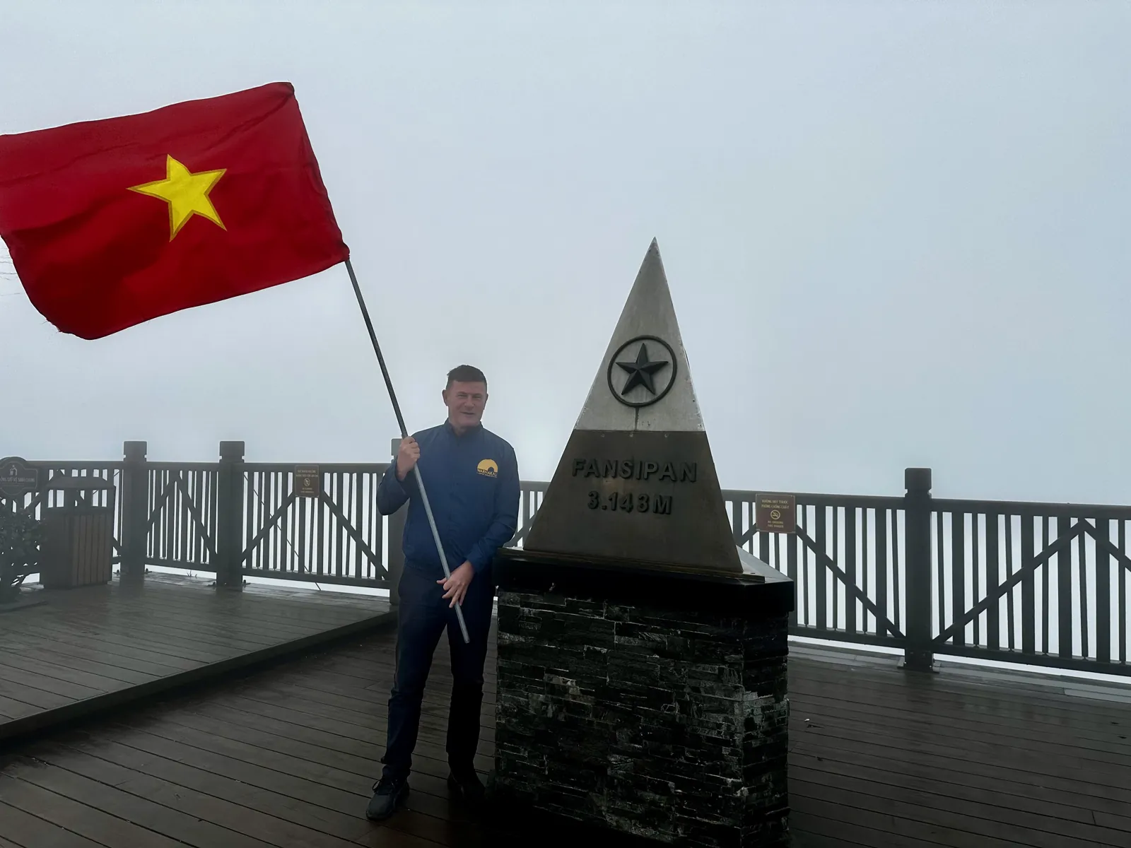 Met een Vietnamese vlag naast de topmarkering van de Fansipan op 3143 meter