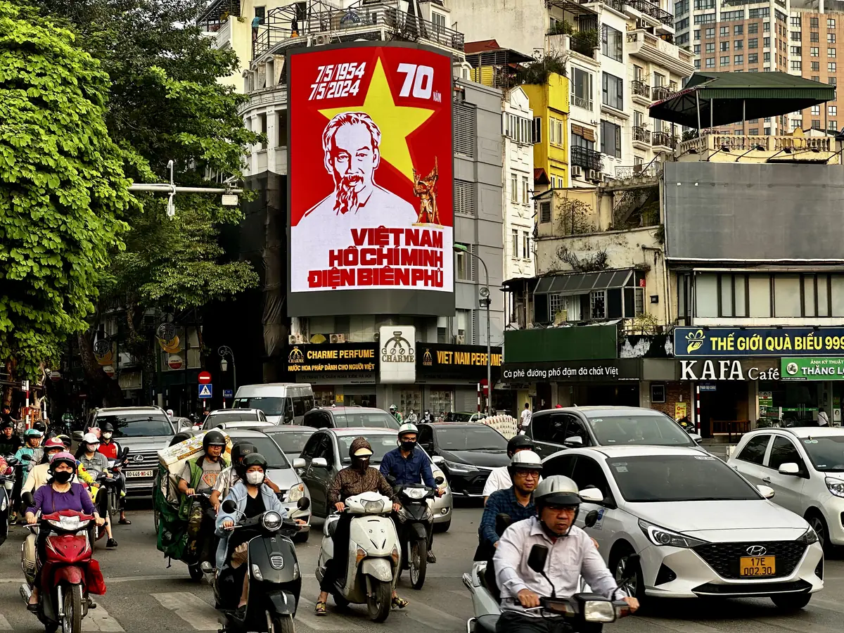 Propagandaposter van Ho Chi Minh boven het scooterverkeer in Hanoi