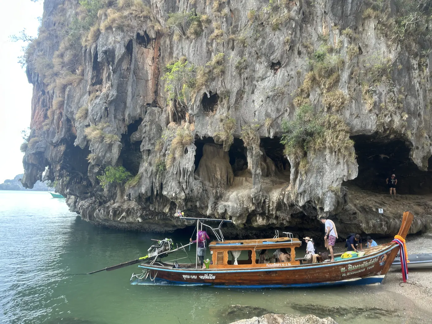 Barca long-tail sotto la parete erosa di Khao Phing Kan, isola di James Bond