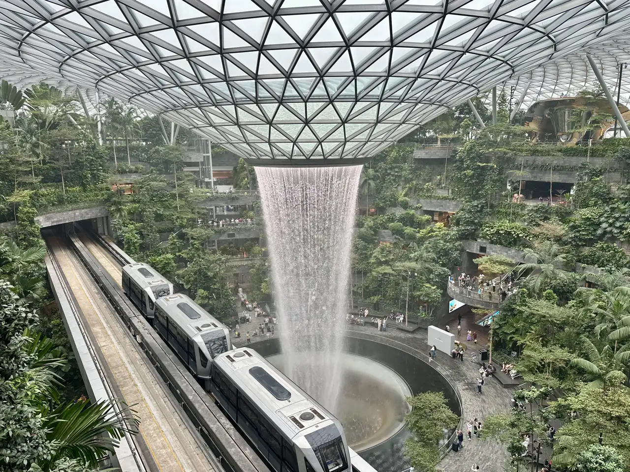 De Rain Vortex in Jewel Changi Airport met de Skytrain die ervoor langsrijdt