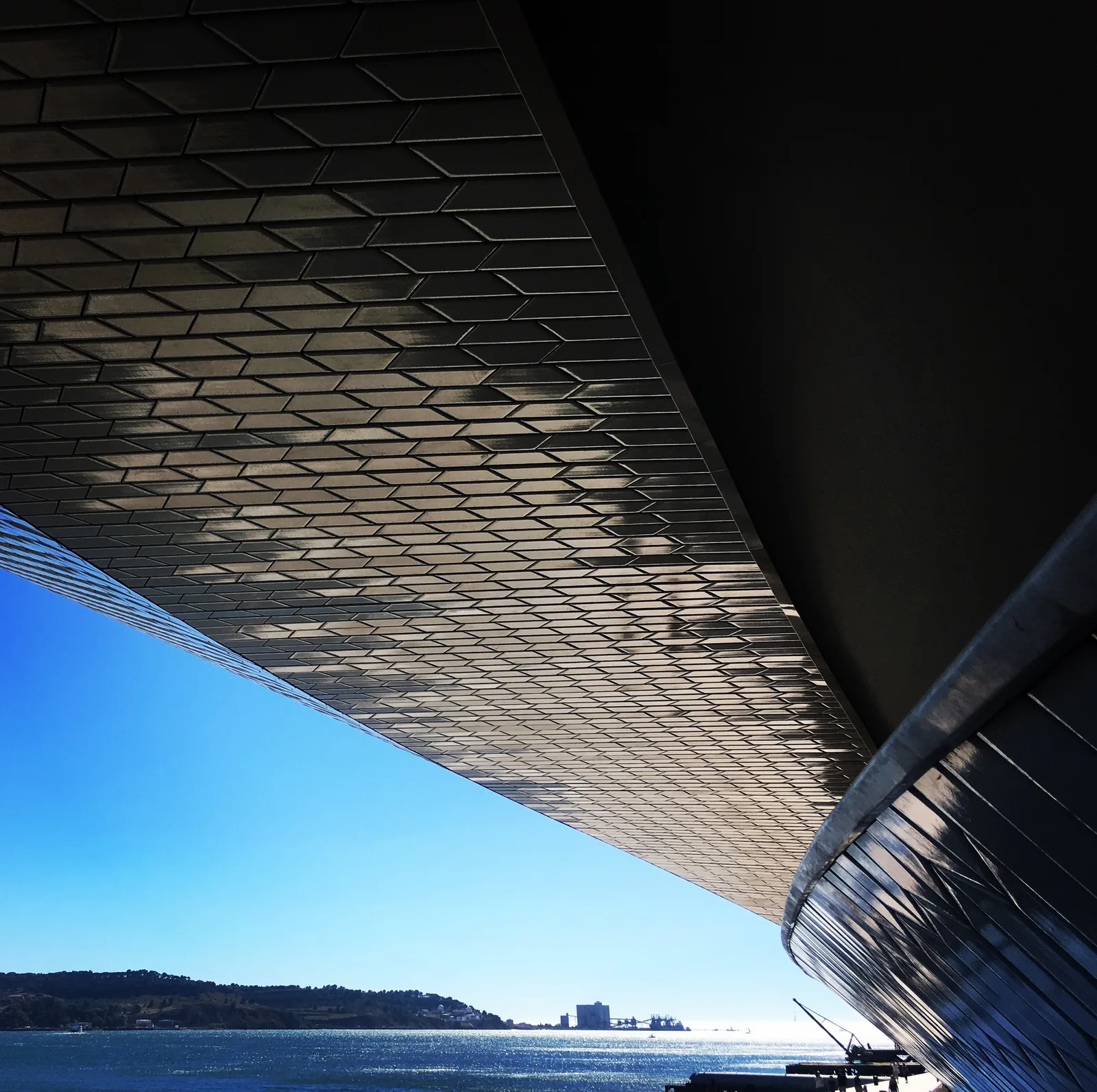 The curved roof of the MAAT museum framing the Tagus in Belém