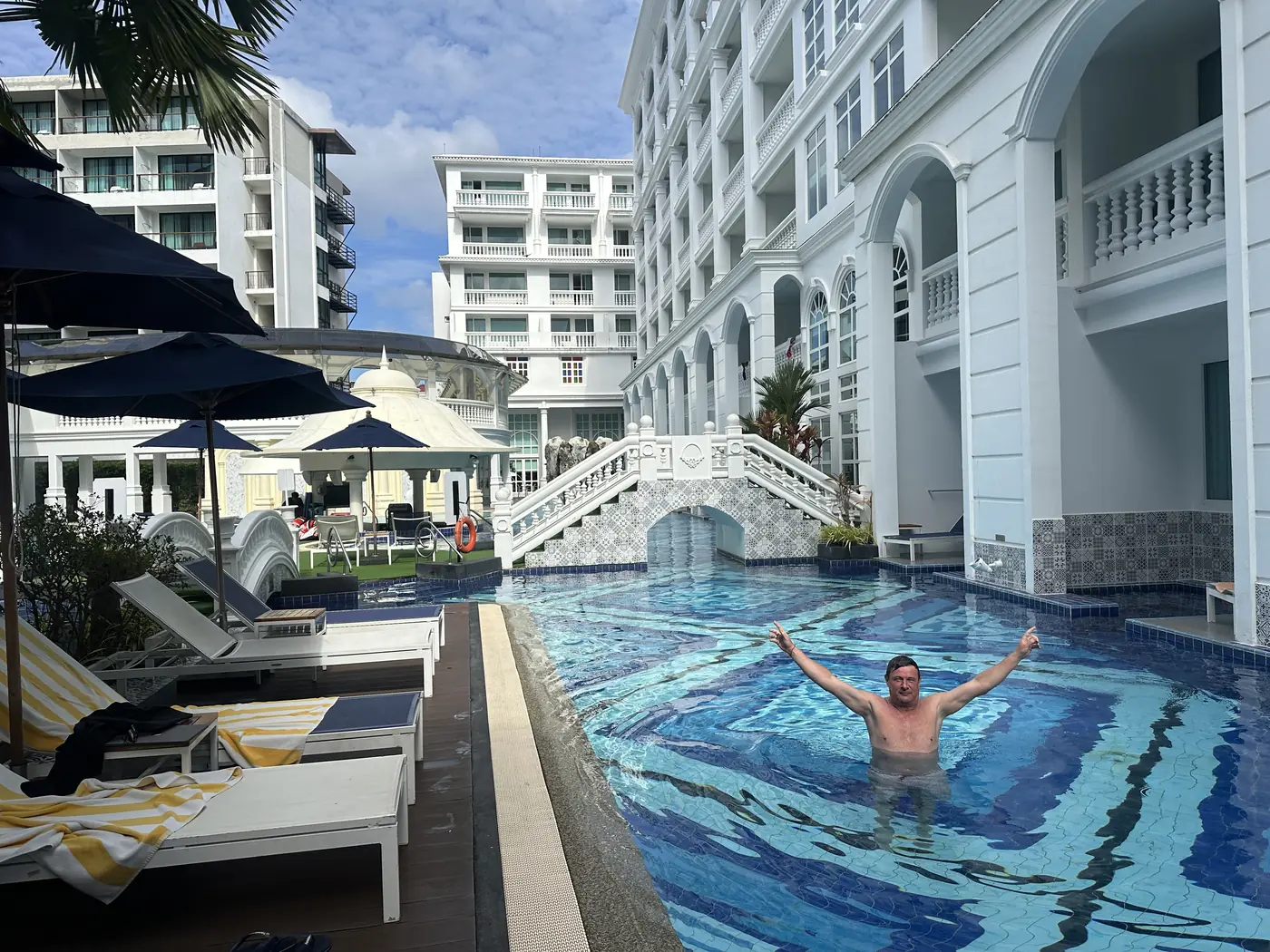 Lang blauw mozaïekzwembad tussen witte gebouwen van het Mövenpick Myth Hotel Patong