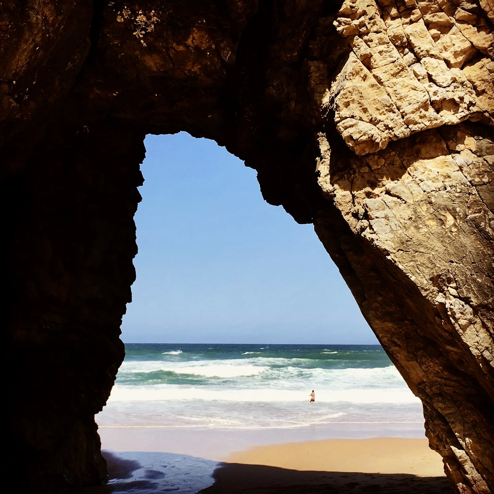 The natural rock arch of the Praia da Adraga framing the beach and the ocean