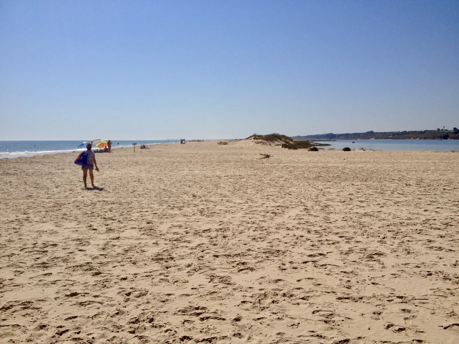 A walker on the long beach of Cacela Velha with the dunes behind