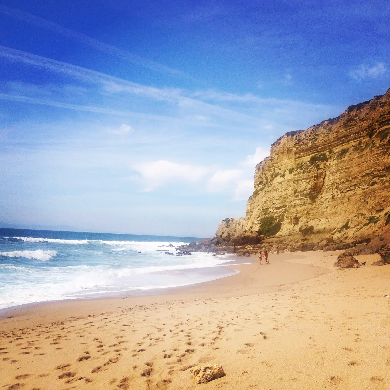 Ochre cliffs and surf on the beach at Meco near Sesimbra