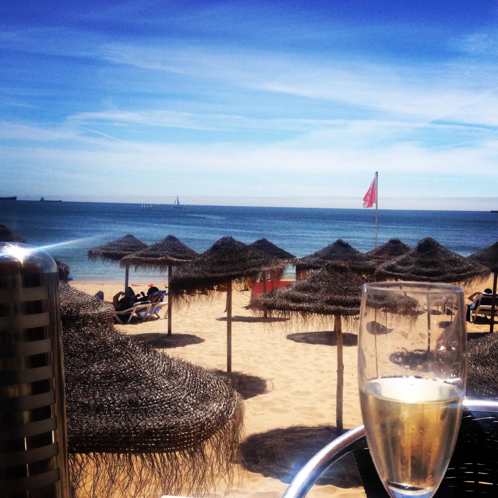 A drink on a beach restaurant terrace with straw umbrellas on the Praia do Tamariz