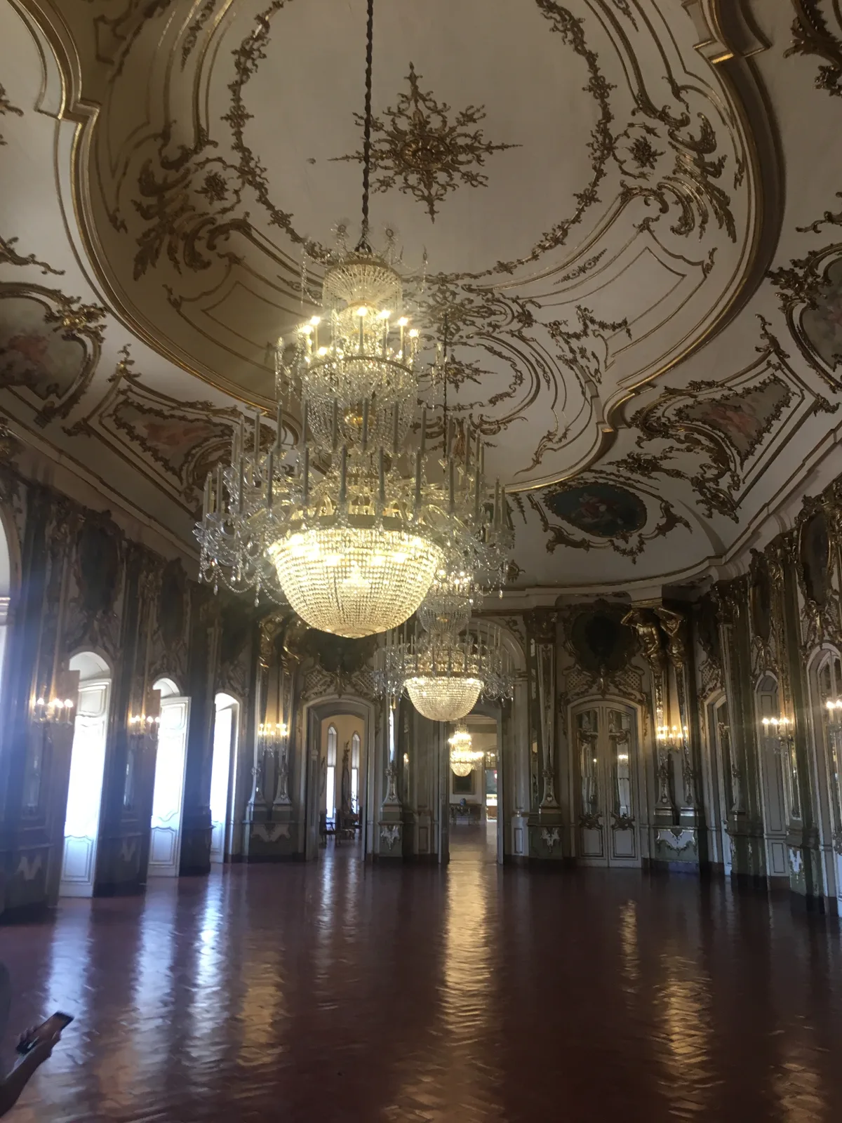 A gilded hall with mirrors and crystal chandeliers in the National Palace of Queluz