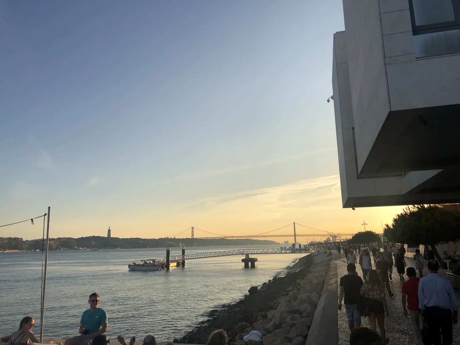 People on the riverside steps of the Ribeira das Naus at sunset