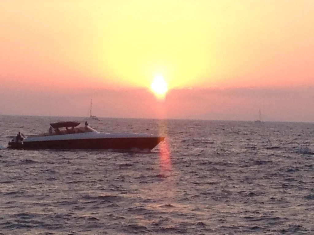 Sunset over the sea with a speedboat off Little Venice, Mykonos