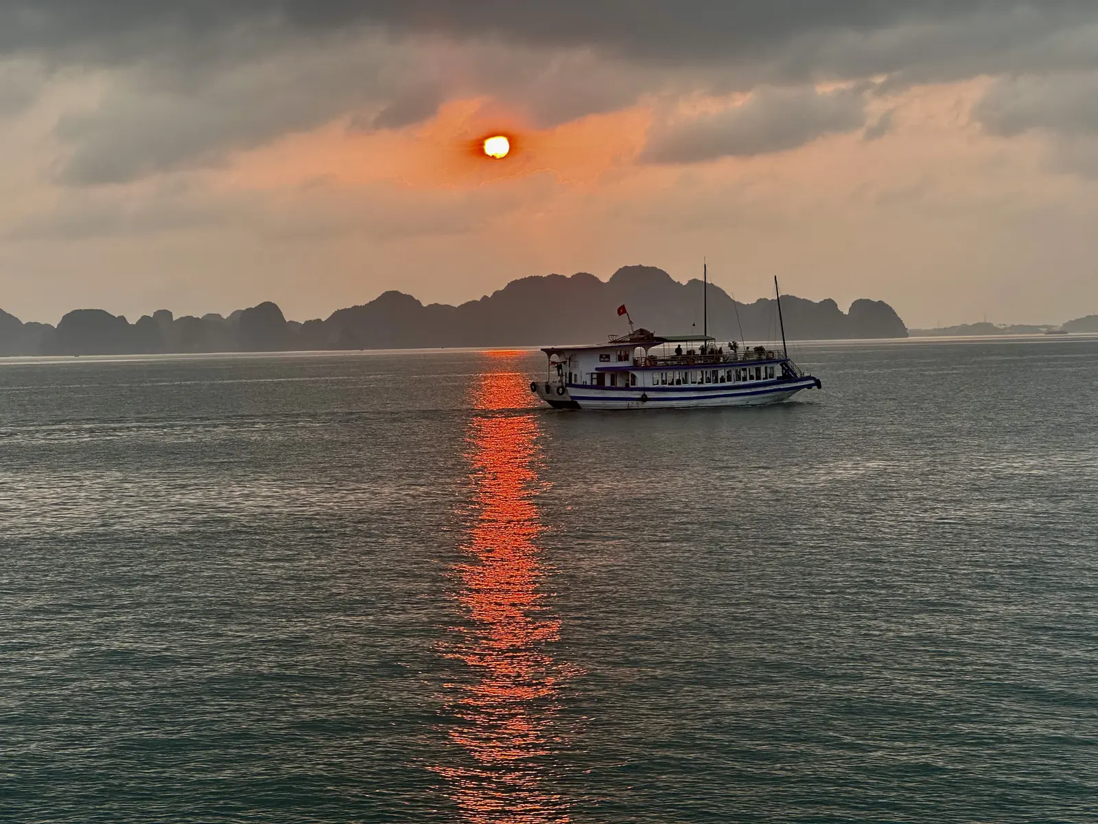 Zonsondergang boven de karsteilanden van de Halongbaai vanaf een cruiseboot