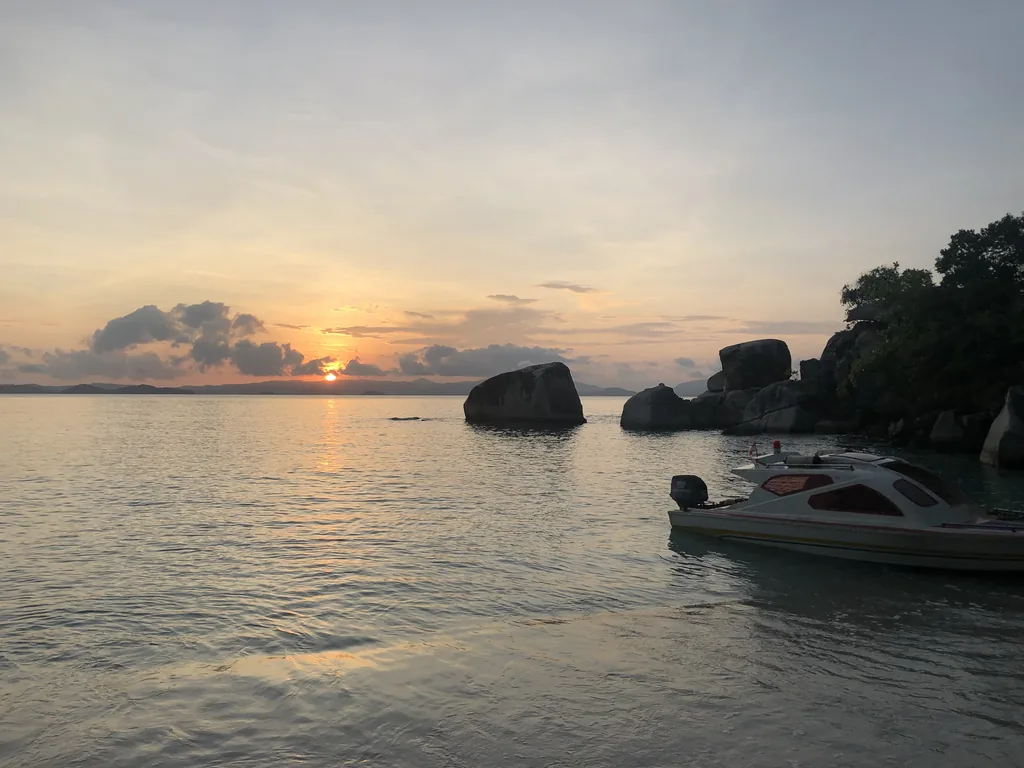 A speedboat at sunset among granite boulders in the Anambas Islands
