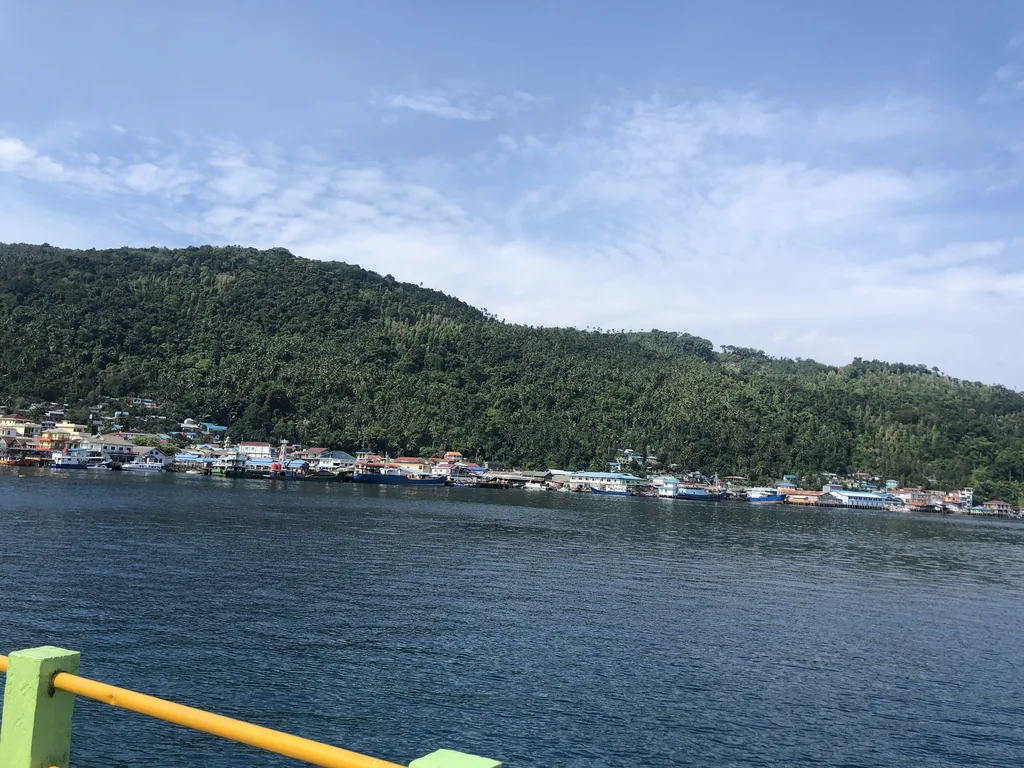 The harbor of Tarempa with its houses on stilts and green hills, Anambas Islands