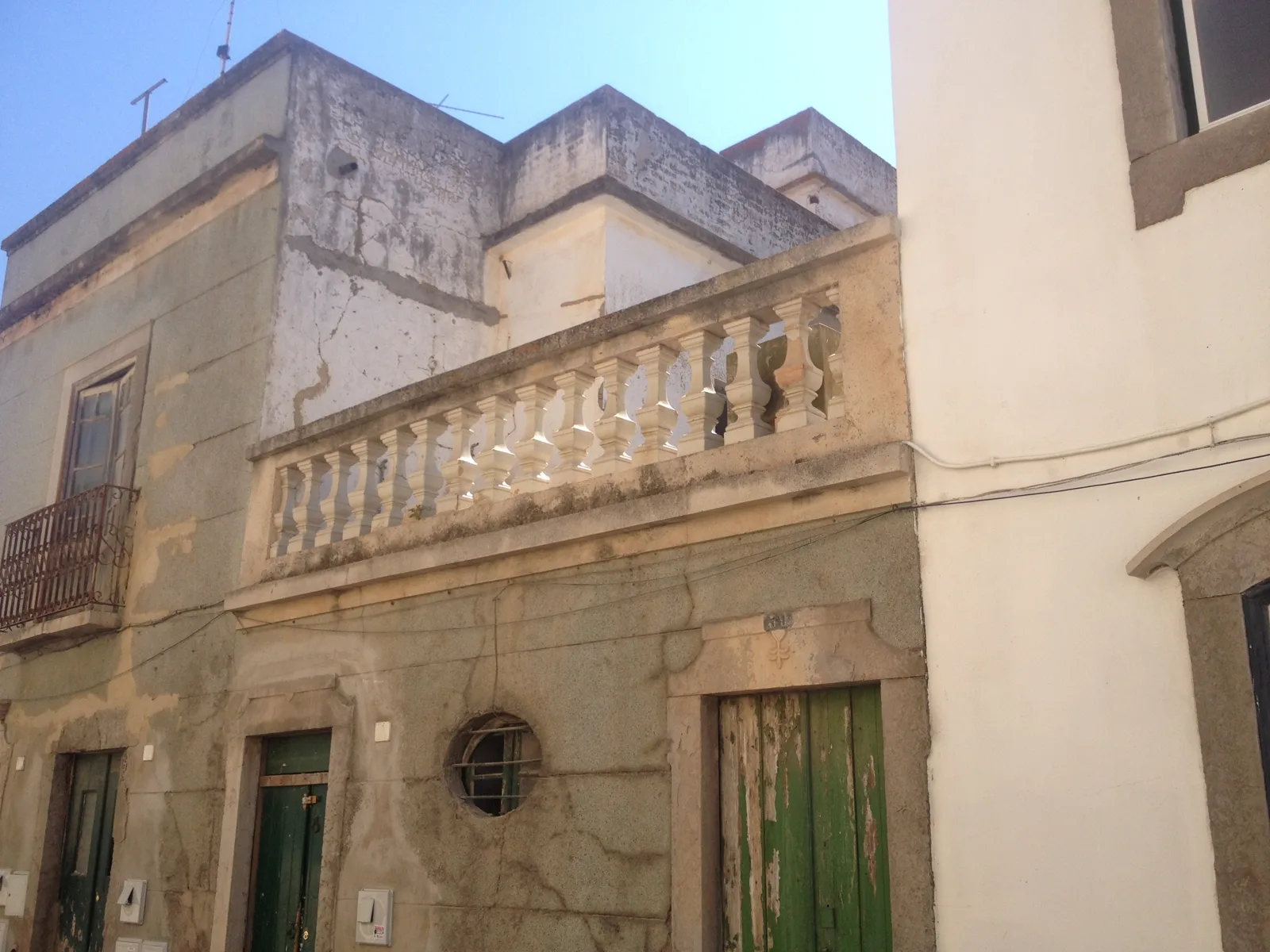 An old house with a stone balustrade and green doors in Tavira