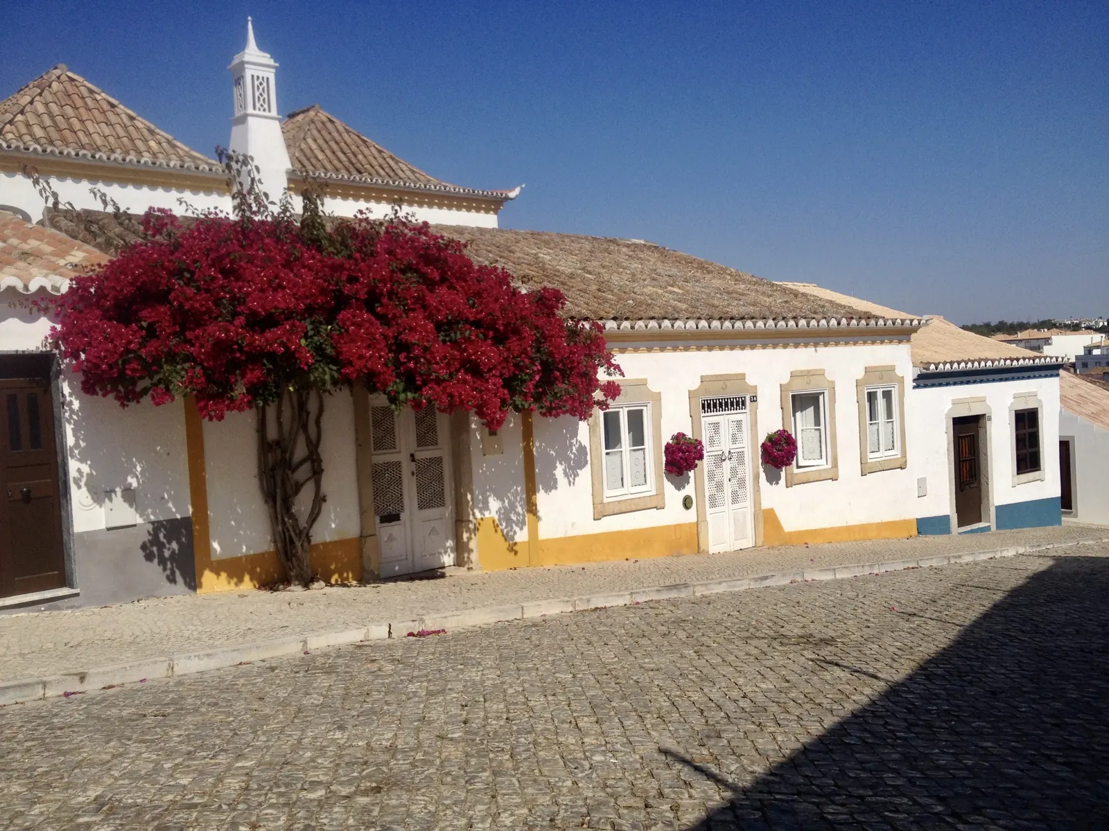 A white house covered in red bougainvillea on the Calçada de Dona Ana in Tavira