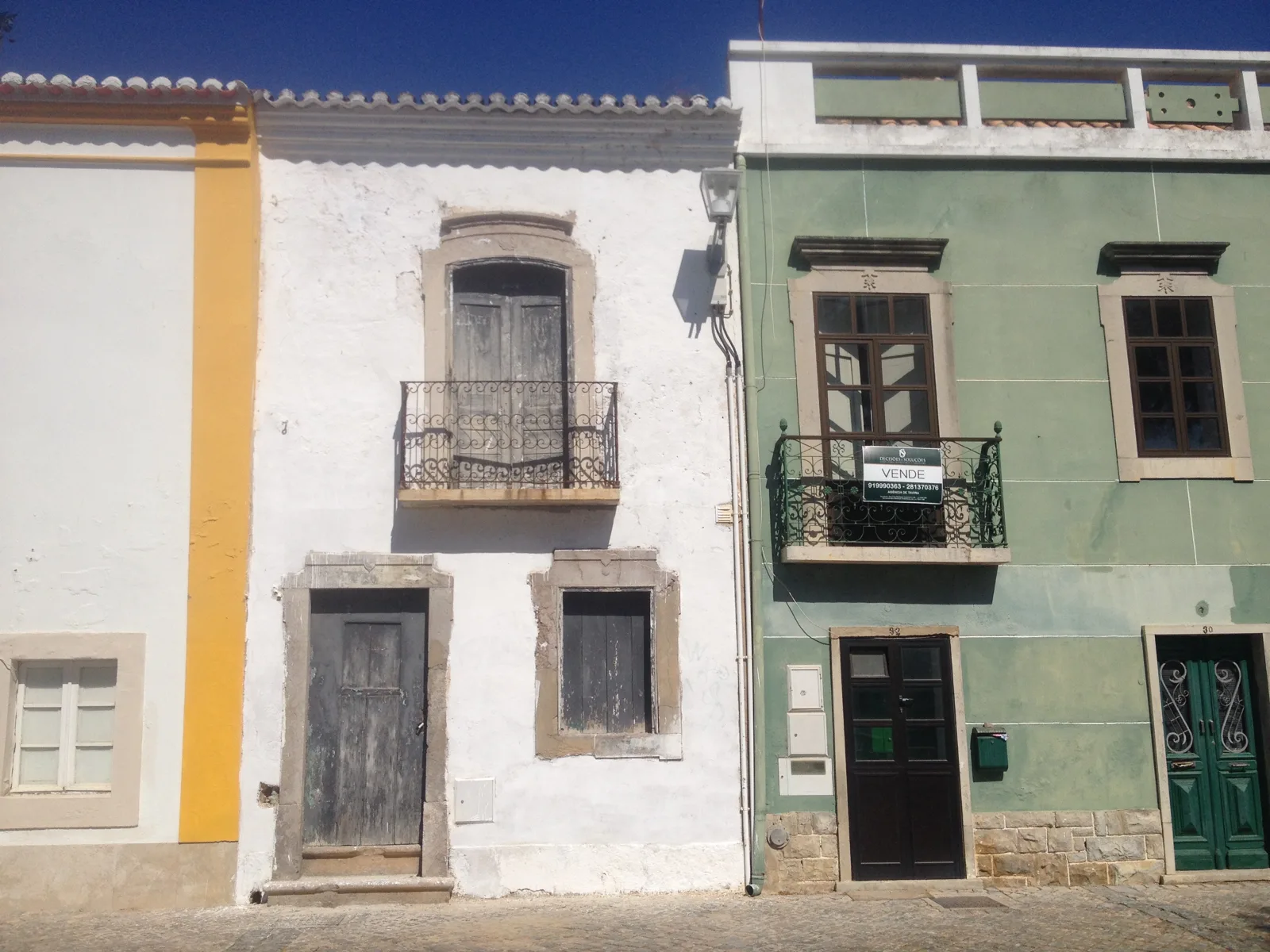Old white and green facades with iron balconies in Tavira