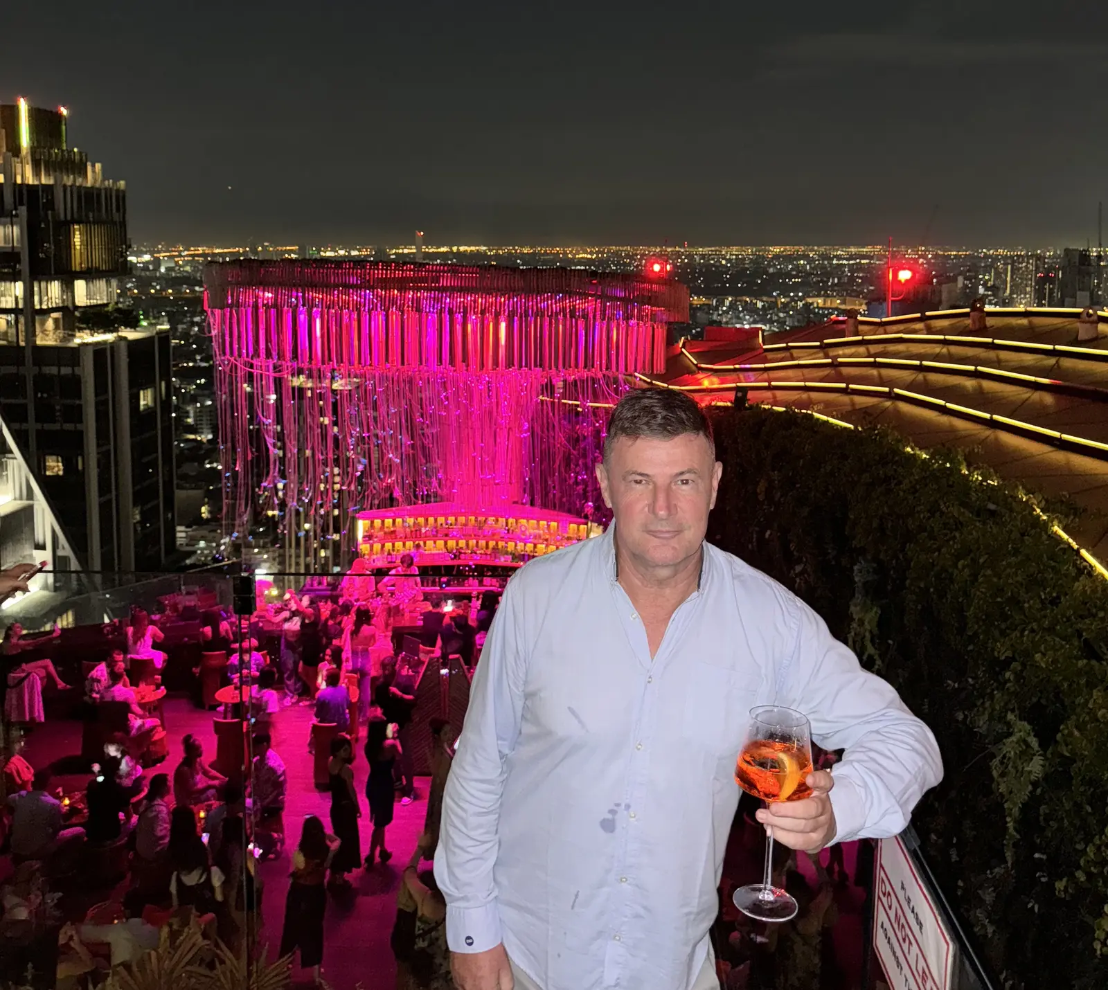 Blaise Jaeger with a cocktail at Tichuca rooftop bar under its pink light installation, Bangkok