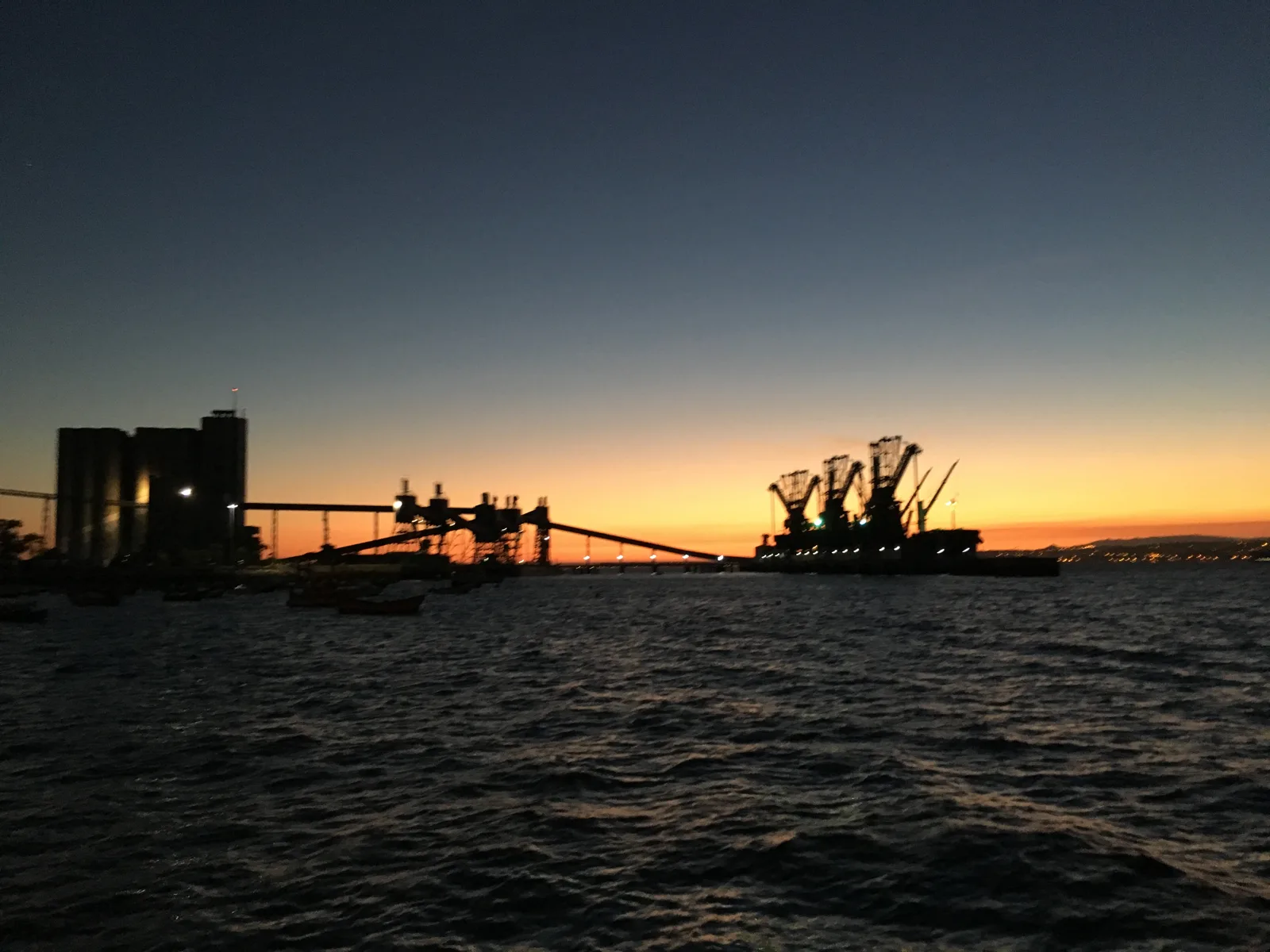 Sunset over the Tagus behind the silhouettes of the silos of Trafaria