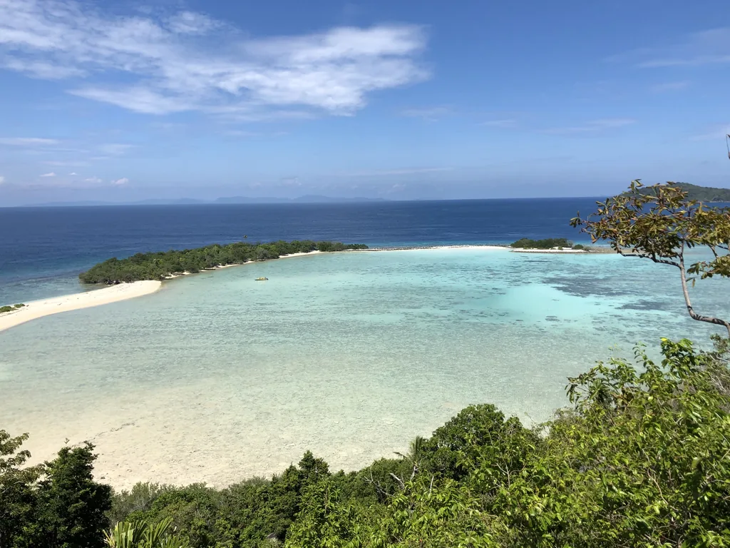 A turquoise lagoon and white sand spit seen from a hill in the Anambas Islands