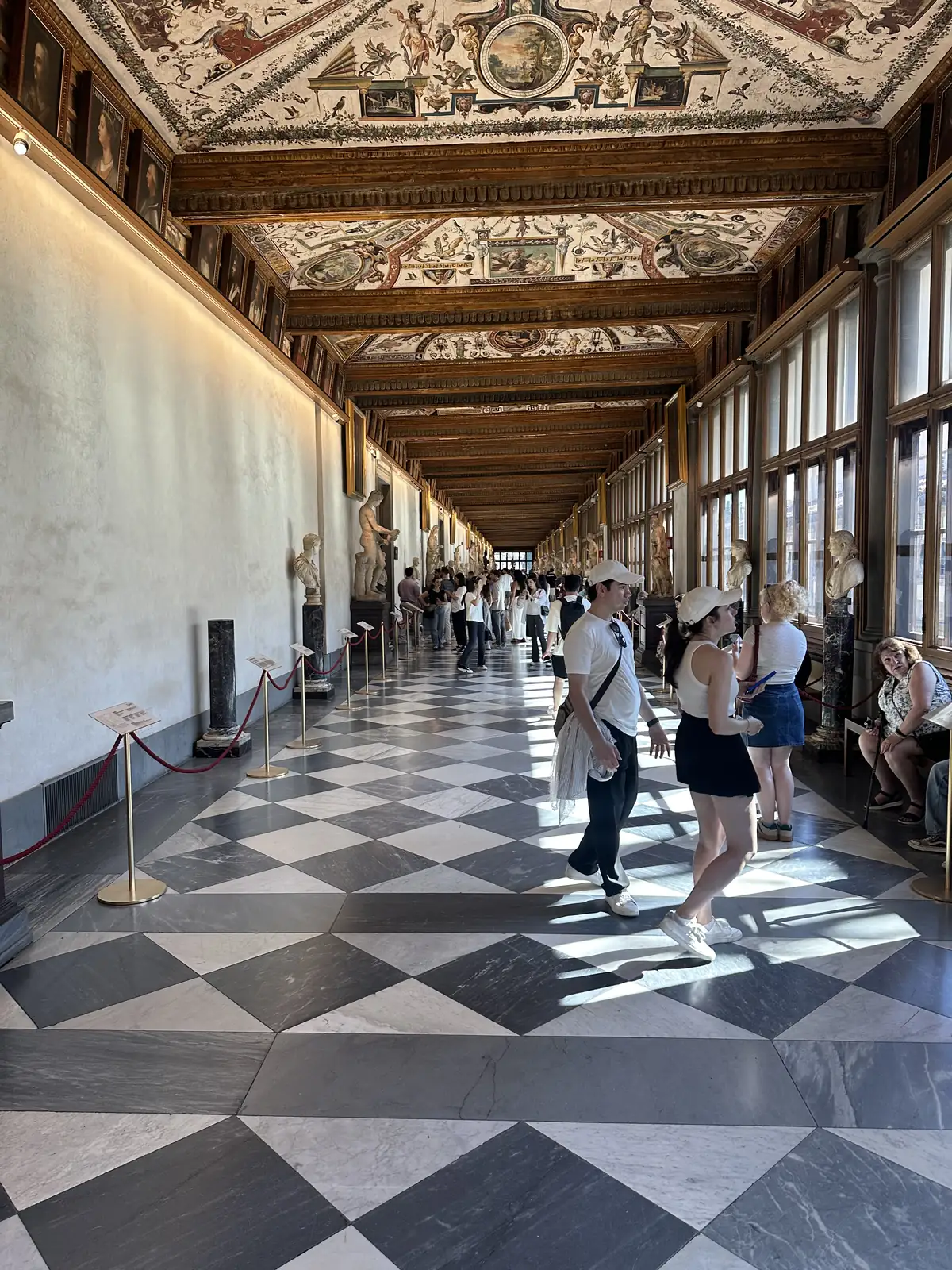 The long corridor of the Uffizi Gallery with its painted ceiling and checkered floor